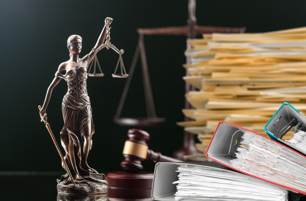 lady justice on desk piled with files with scales and gavel in the background