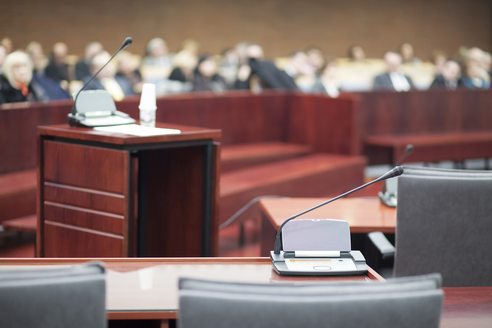 view of witness stand in a courtroom with crowd looking on