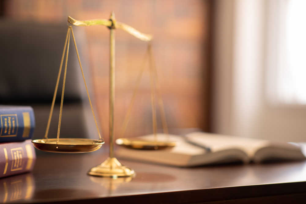 scales of justice and law books on lawyer desk at law firm.