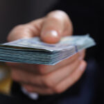 closeup of hand offering cash
