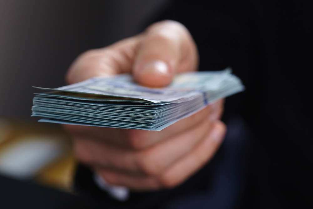 closeup of hand offering cash