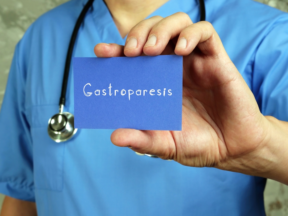 male doctor holding a blue notecard that reads Gastroparesis