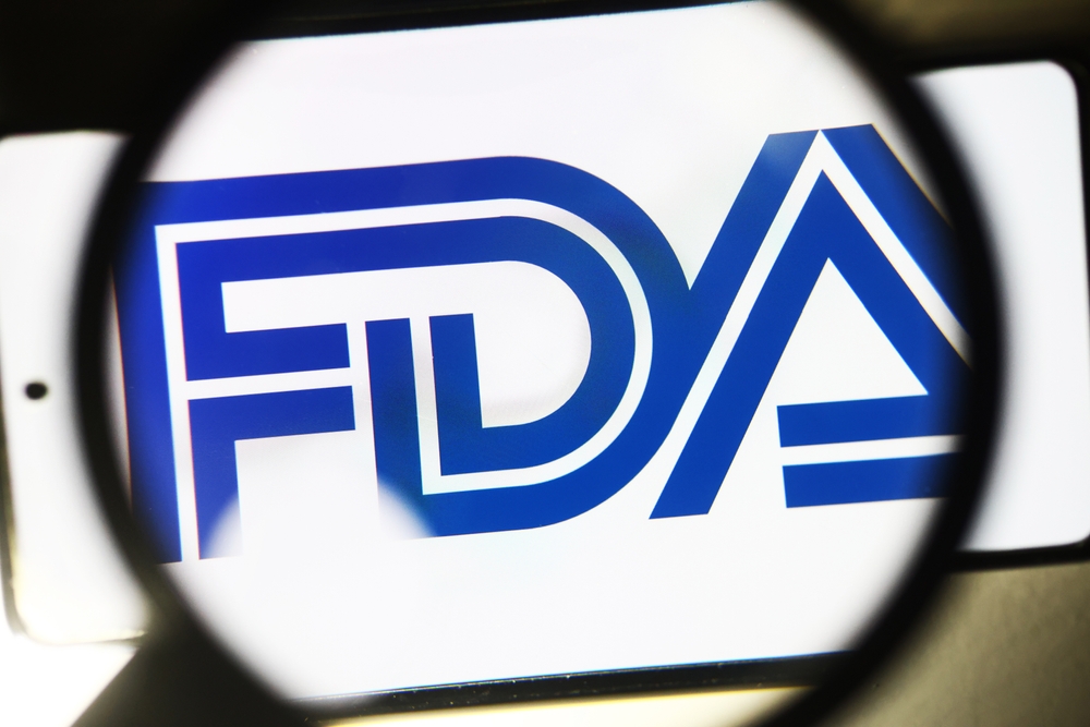 closeup of FDA logo on a smartphone viewed through a magnifying glass