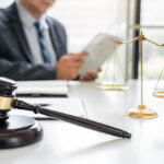 an attorney working at a white desk with a gavel and scales of justice in foreground