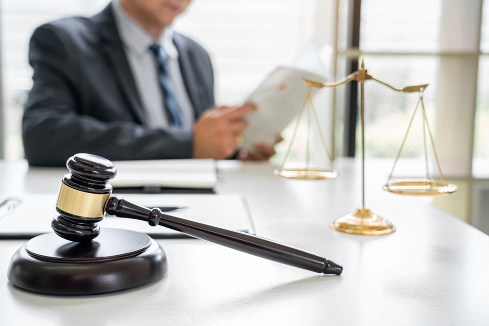 an attorney working at a white desk with a gavel and scales of justice in foreground