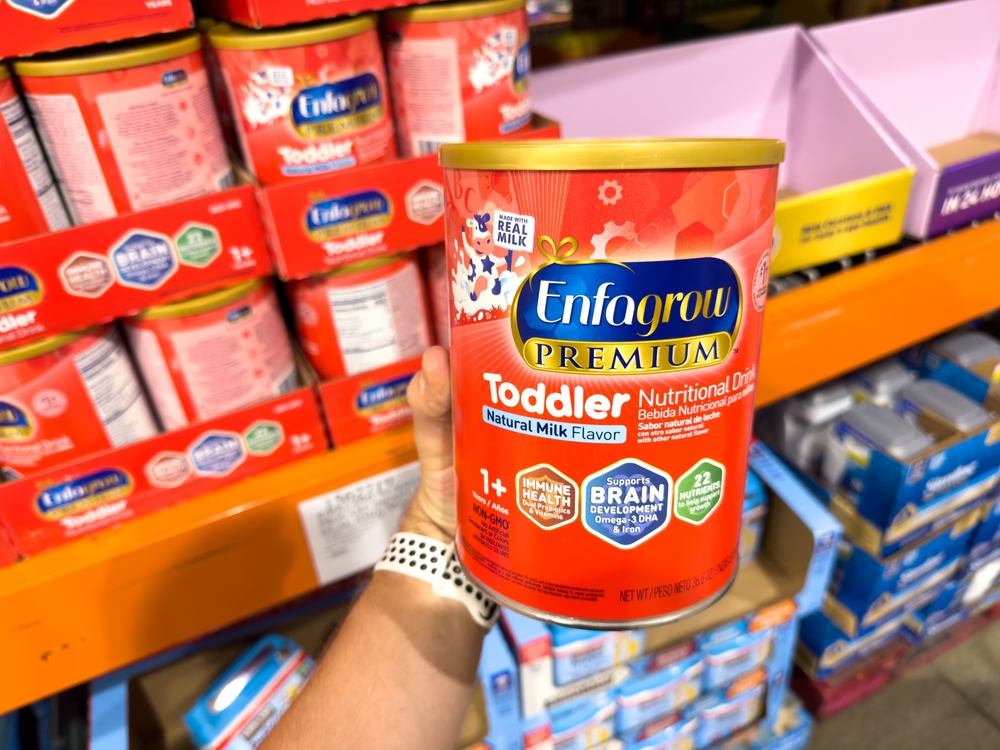 person holding Enfagrow Premium Toddler Nutritional Drink powder in aisle at store