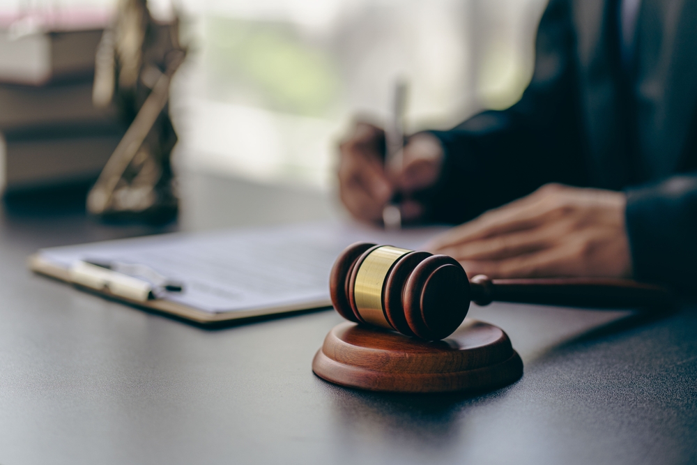 selective focus on gavel on an attorney's desk with blurred lawyer working behind