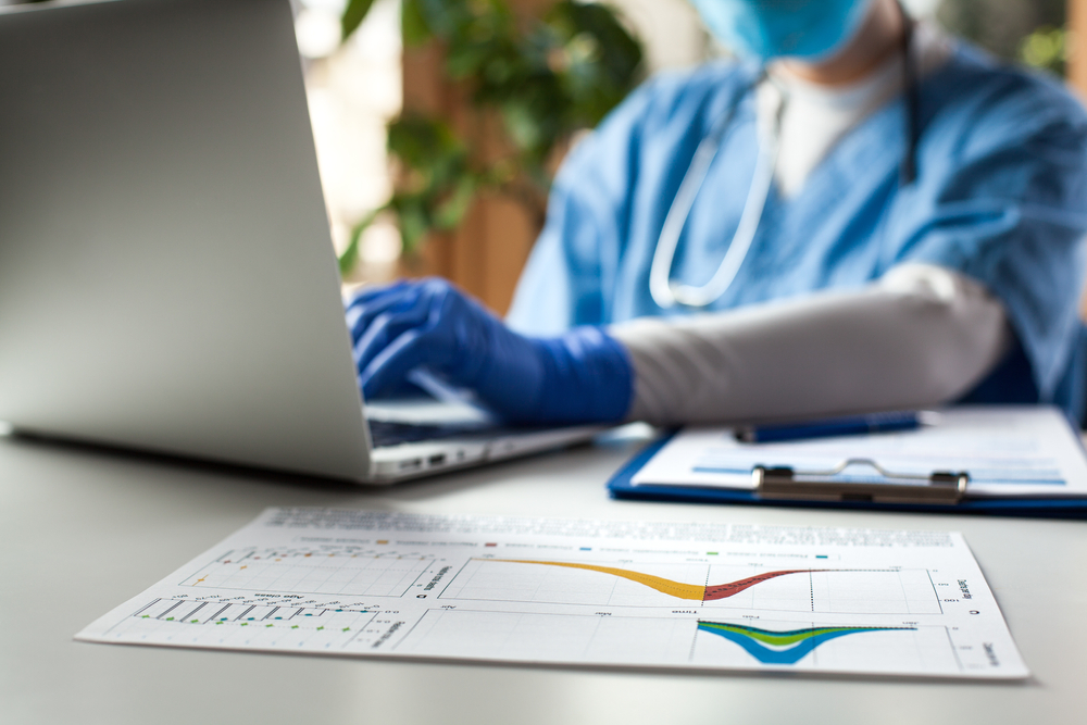 Epidemiologist doctor working on laptop computer analyzing graphs and charts