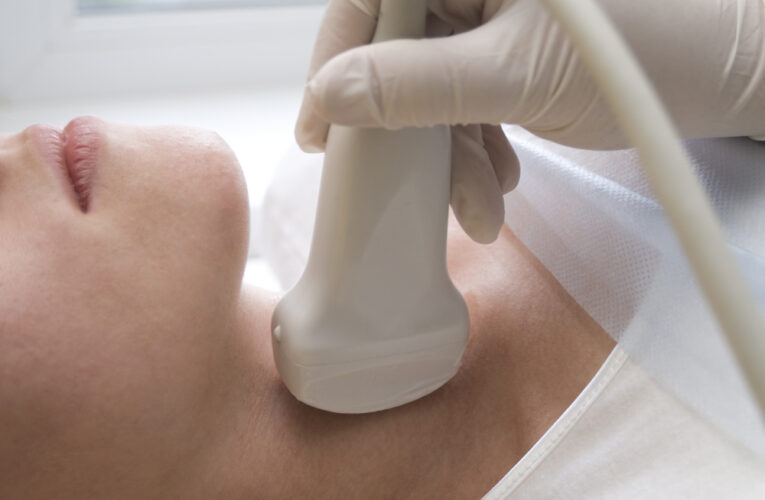closeup of an endocrinologist scanning a woman's thyroid