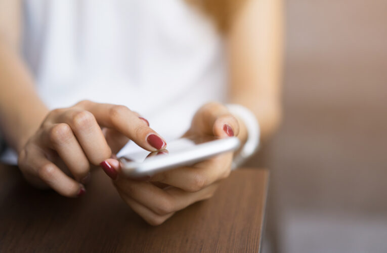 closeup of a young woman using her smartphone at a desk