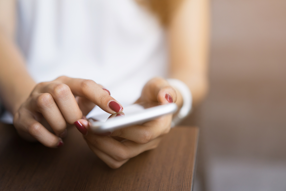 closeup of a young woman using her smartphone at a desk