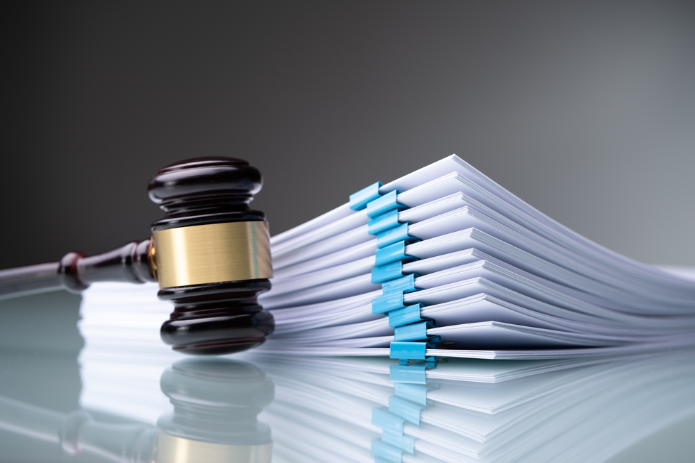 a gavel on a glass top table with clip bound paper stacked behind