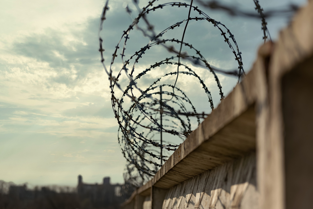 closeup view of a prison wall with barbed wire