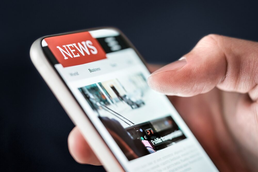 closeup of a hand holding phone reading daily news